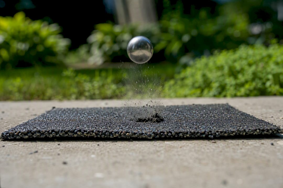 Steel ball impacting asphalt shingle in test